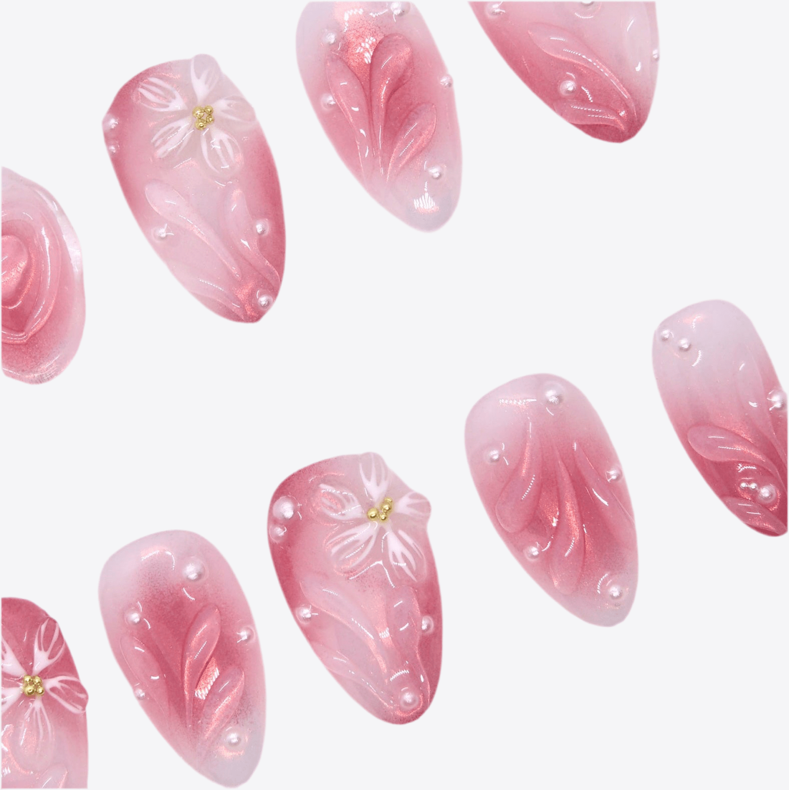 Close-up of sculpted flowers and pearls on pink gradient press-on nails.