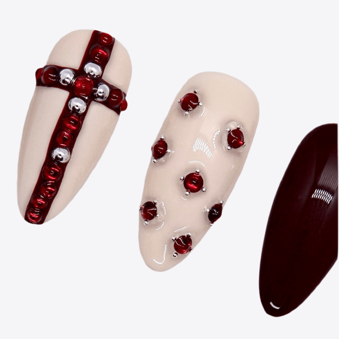 Deep wine-colored nails paired with porcelain beige and gemstone accents